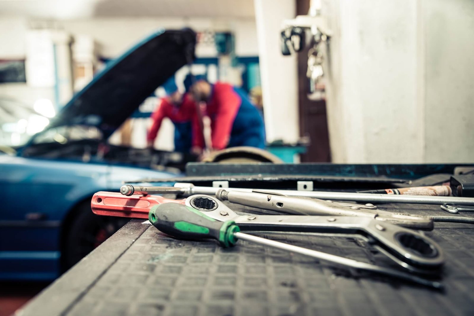 Professional mechanics working on a vehicle in a modern auto repair shop, with specialized tools on a workbench in the foreground