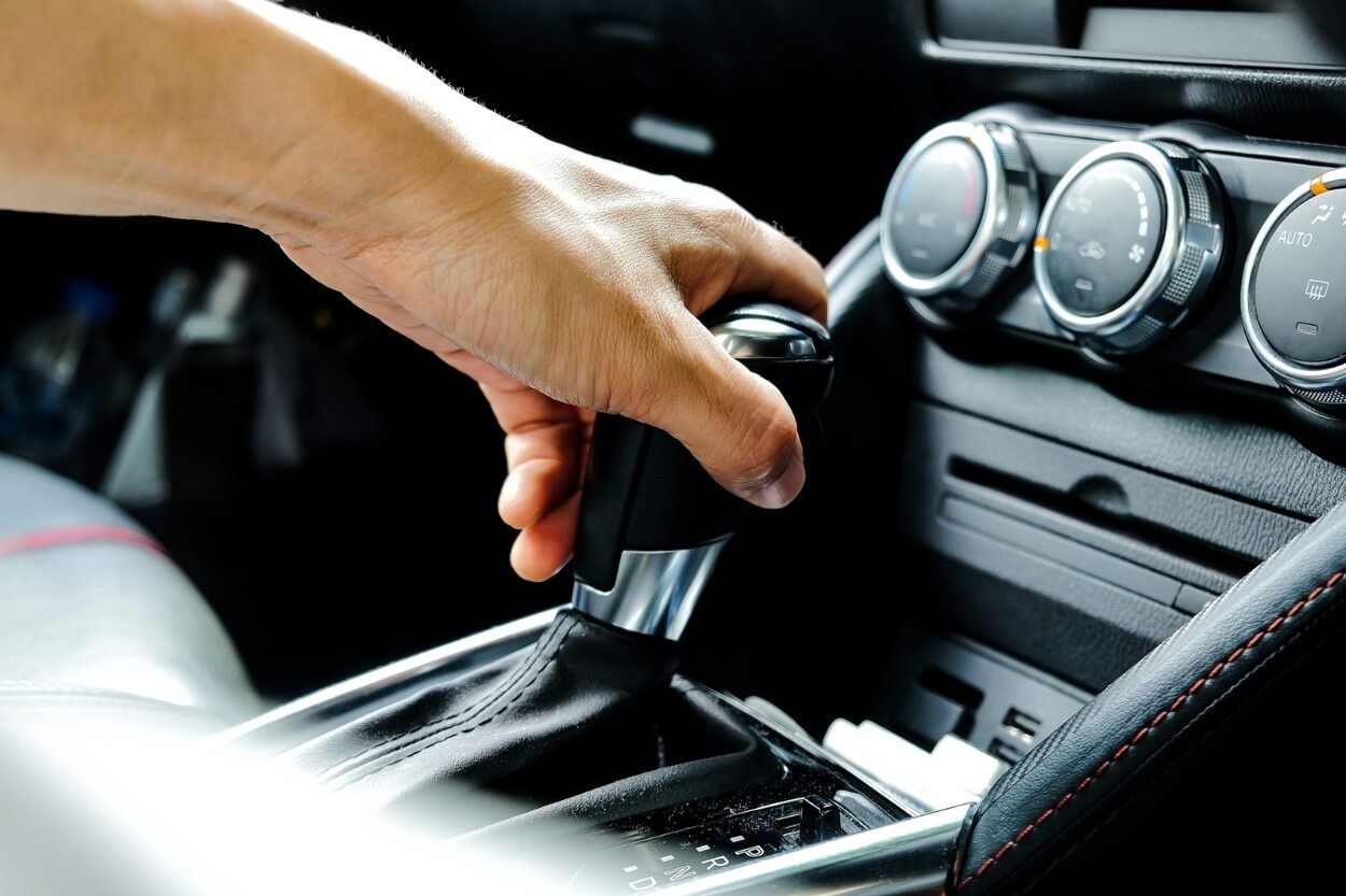 Close-up of a man's hand placed on a gear shifter in a vehicle interior