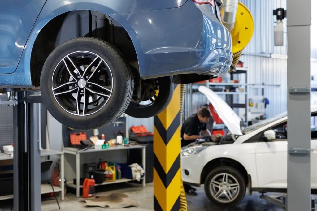A blue car raised on a hydraulic lift in a professional service bay, highlighting the specialized equipment used for transmission repair and under-vehicle inspections.