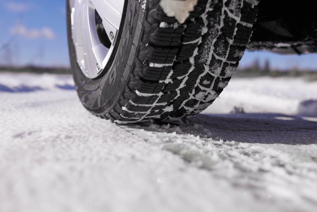 Close-up of a high-traction winter tire driving on a snow-covered road.